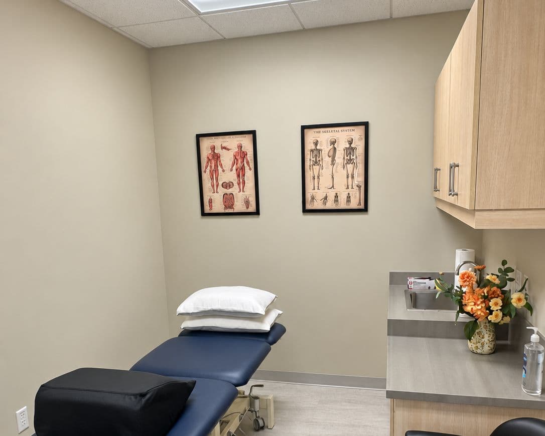 A second treatment room with a treatment table and anatomy charts